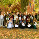Absolventinnen und Absolventen von 2022 der Hochschule Clara Hoffbauer Potsdam vor der Inselkirche mit Zeugnissen und Blumen in der Hand